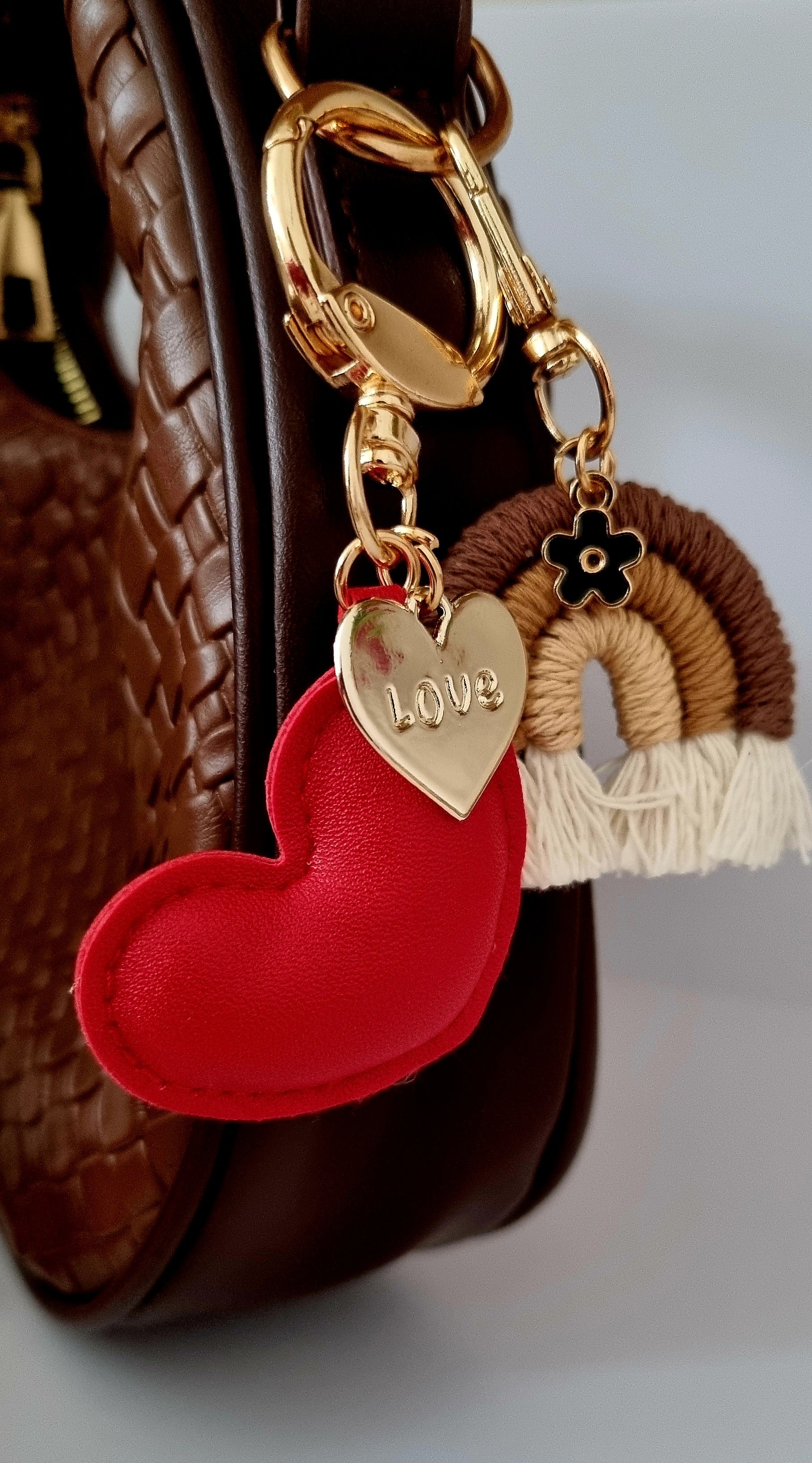 Heart-shaped keychain with 'LOVE' charm attached to a brown textured surface.