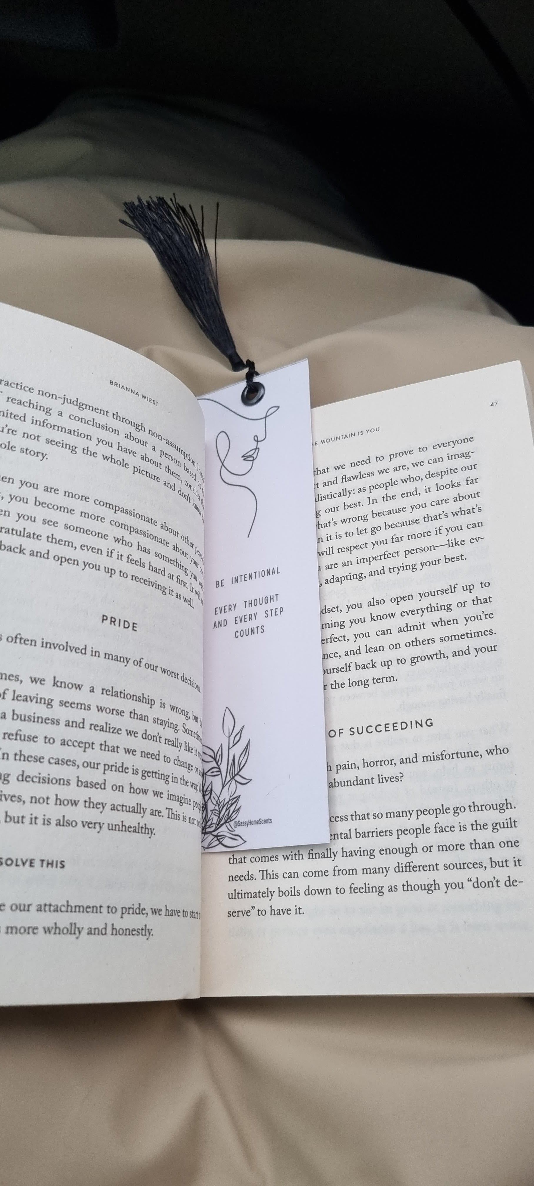 Open book with a bookmark featuring a face illustration on a white surface.