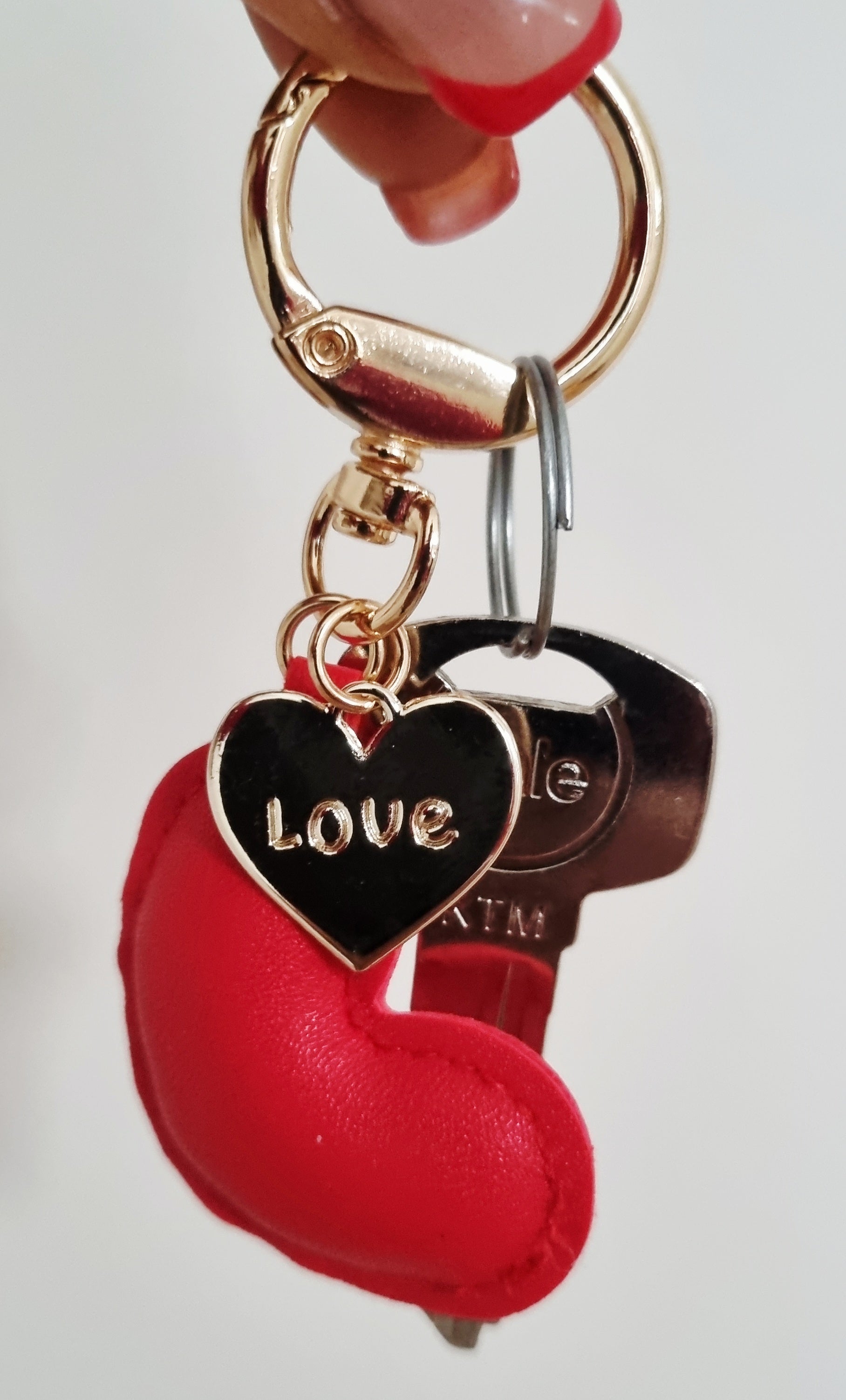 Red heart-shaped keychain with a gold tag on a light white background. Perfect for teenager, adults and kids for backpacks, handbags and keys